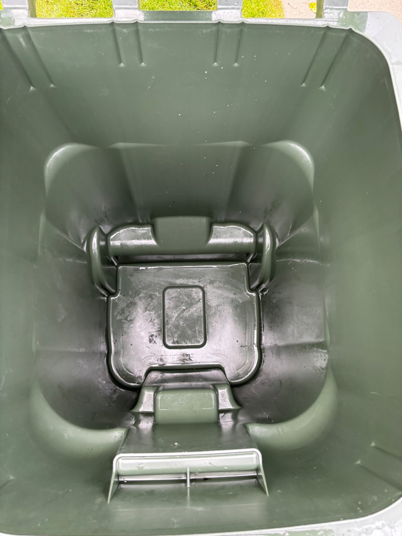 Technician hot-water washing the inside of a residential trash can